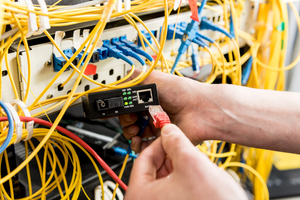 Network engineer working in server room. Connecting network cables to switches